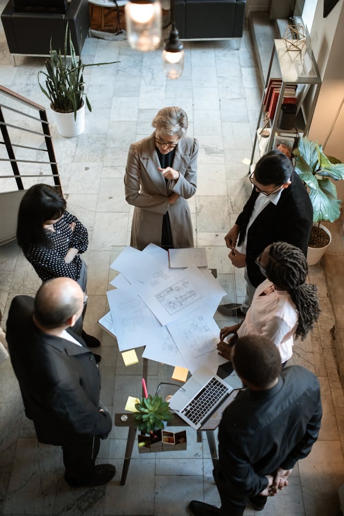 service-01 A diverse group of professionals collaborating over documents in a modern office setting.