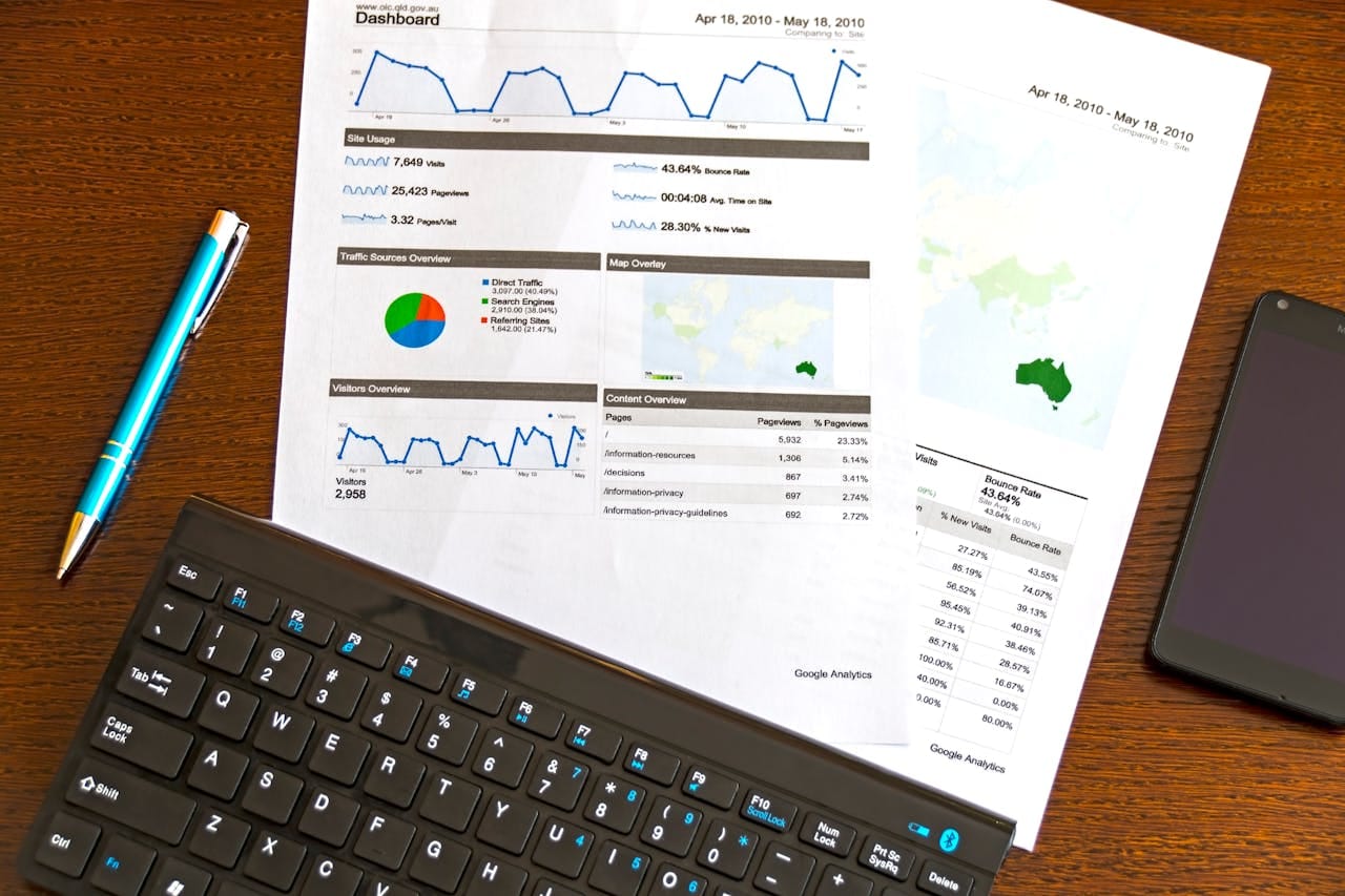 service-04 Flatlay of a business analytics report, keyboard, pen, and smartphone on a wooden desk.