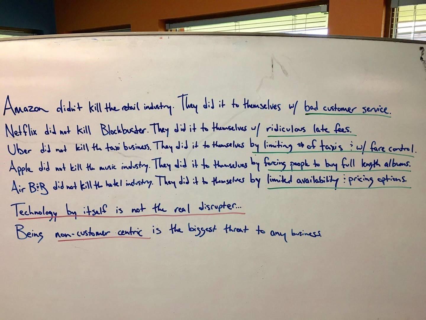 Handwritten whiteboard list: Amazon did not kill retail, Netflix did not kill Blockbuster, Uber did not kill taxis, Apple did not kill music, Airbnb did not kill hotels. They did it to themselves. Being non-customer-centric is the biggest threat to any business.